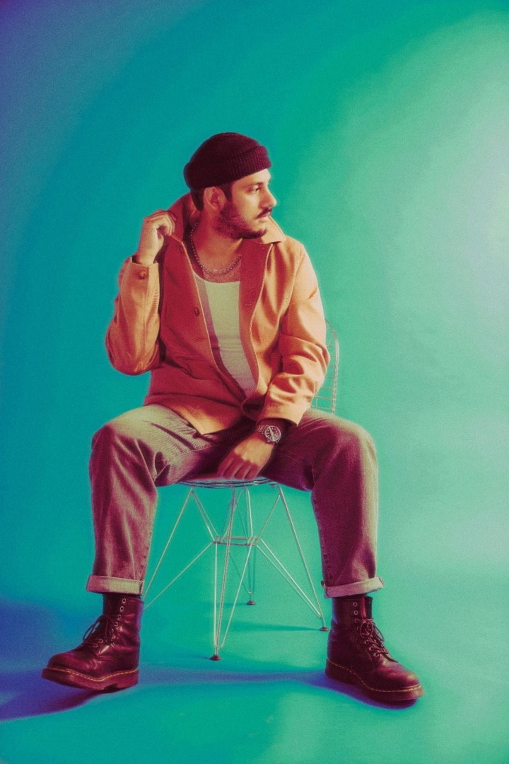 Ookay posing upon a stool on a light green background